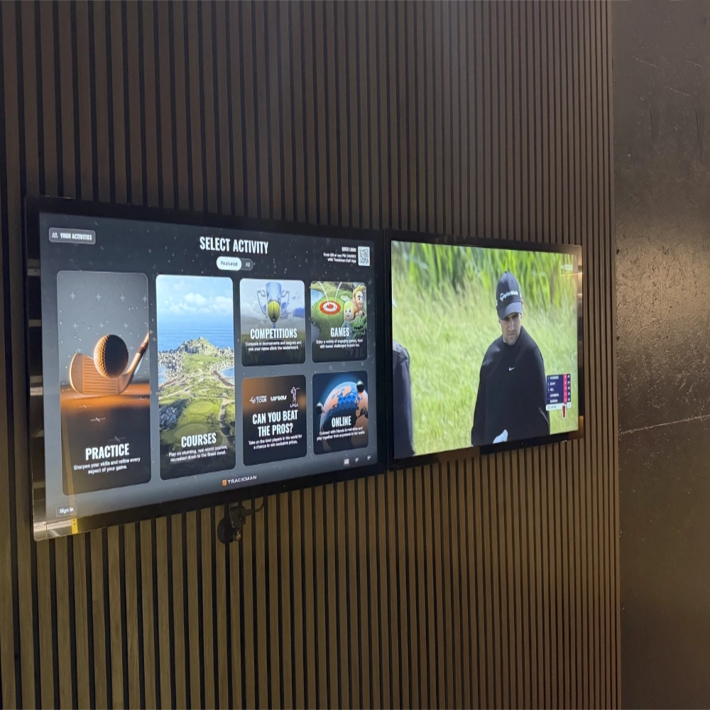 Two iiyama ProLite TF4339AS-B1AG touchscreens mounted on a wall, showing TrackMan TPS software on the main screen and Sky Sports on the secondary screen.